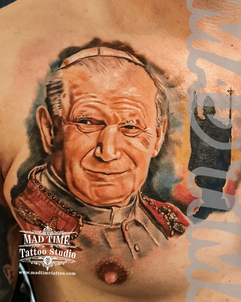 colour-realism-tattoos-liverpool Highly detailed color realism portrait tattoo of Pope John Paul II with realistic facial features and white hair, inked on an arm by Mad Time Tattoo.