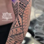 Home new Close-up of a black ink Maori inspired tattoo on the inner arm with heavy geometric shading and triangles.