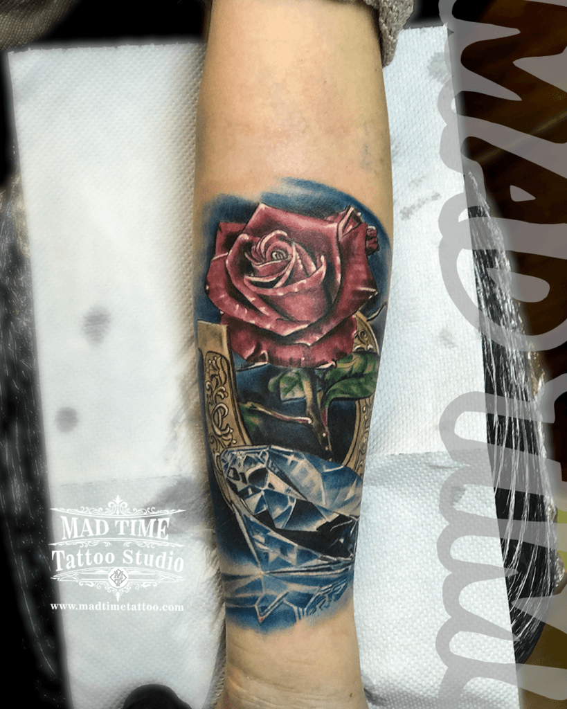 colour-realism-tattoos-liverpool Stunning color realism forearm tattoo by Mad Time Tattoo, featuring a highly detailed dark red rose with green leaves, positioned above a brilliant blue diamond gemstone with sharp crystal reflections.