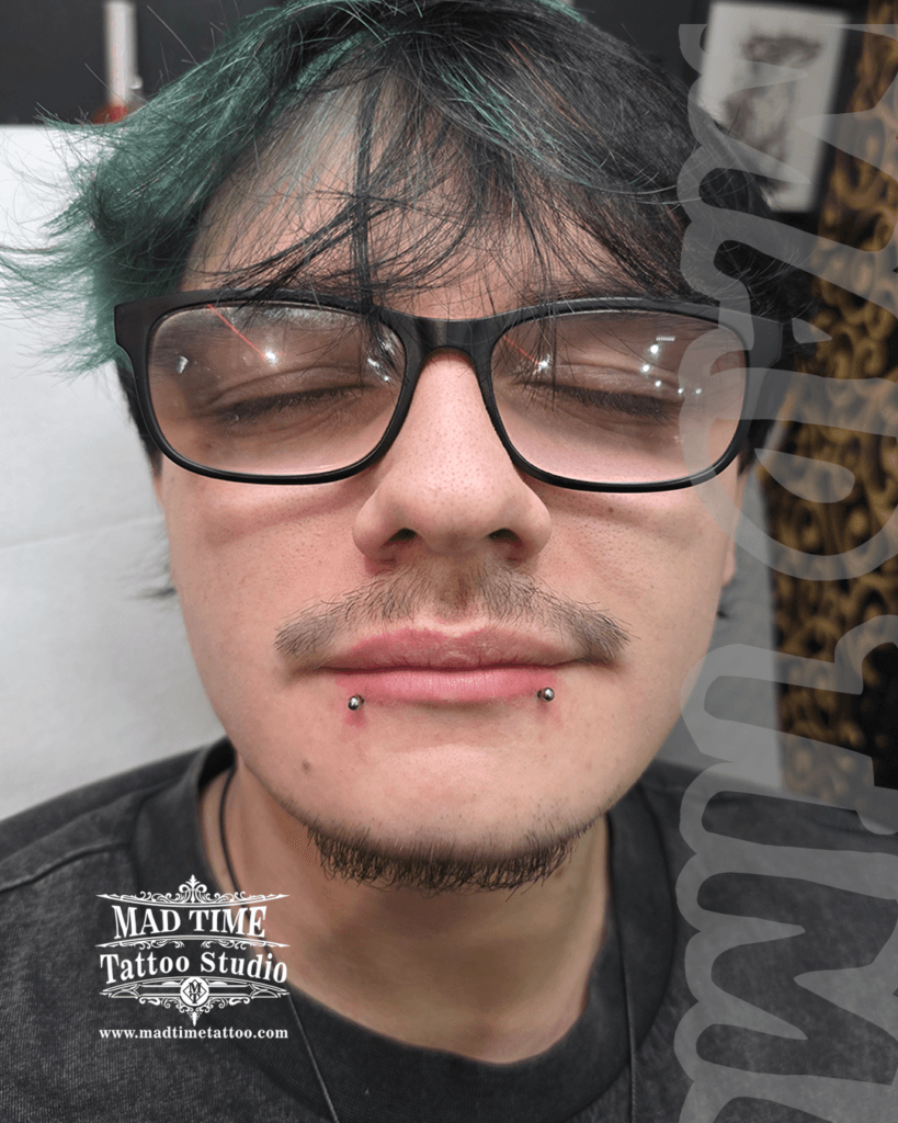 Professional snake bites lip piercing showcase at Mad Time Tattoo Studio, featuring a male client with perfectly symmetrical titanium labret studs on both sides of his lower lip.