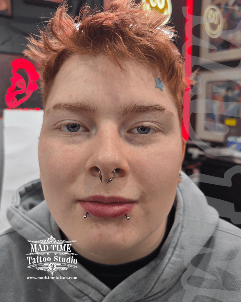 Professional body piercing showcase at Mad Time Tattoo Studio, featuring a client with perfectly leveled snake bites lip piercings and a bold titanium septum ring with cone spikes.