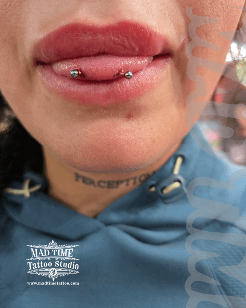 Freshly mapped classic silver snake eyes tongue piercing at Mad Time Tattoo Studio, showing high-polished titanium ball ends with professional surgical marking guides still visible.