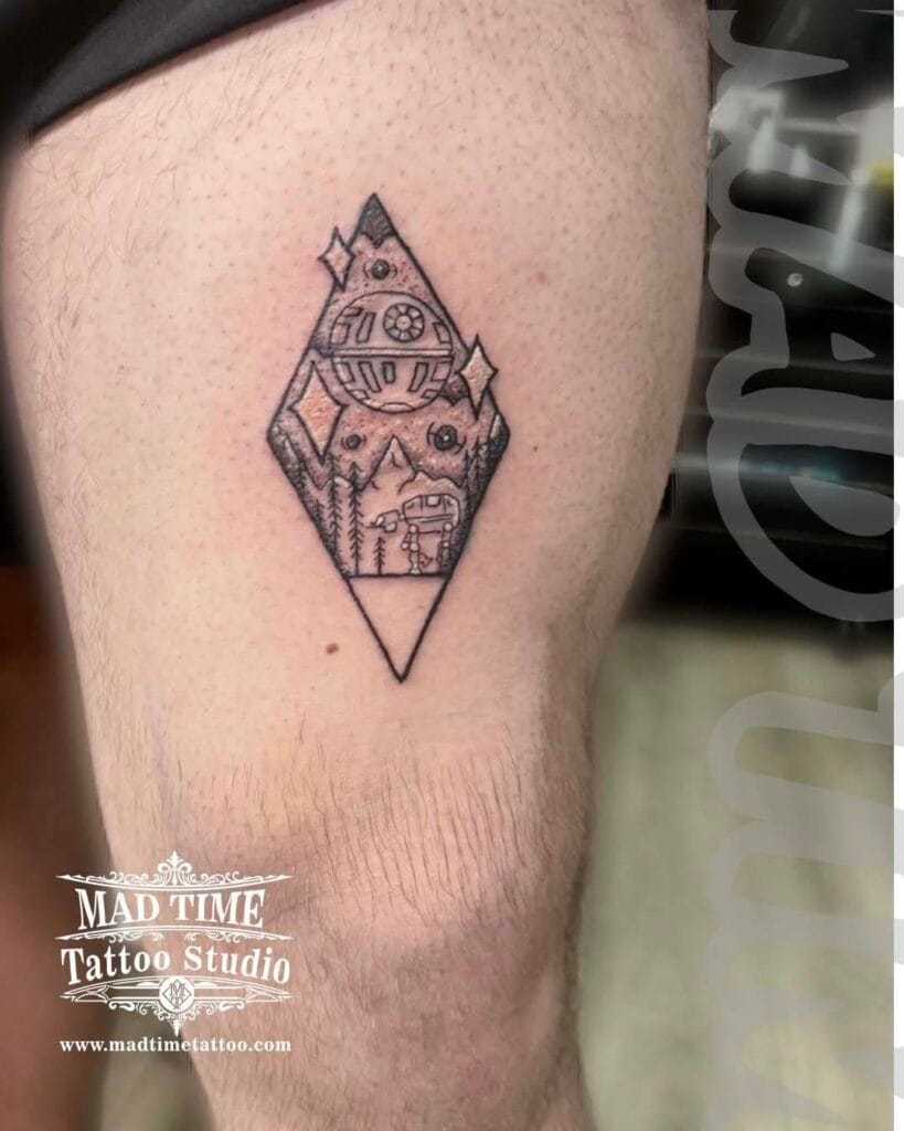 Geometric diamond shaped blackwork tattoo enclosing a detailed Star Wars landscape of Tatooine with twin suns and silhouettes on an arm.