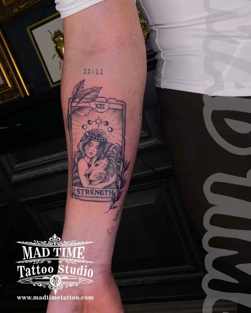 Detailed blackwork tarot card style tattoo featuring a mystical female portrait frame on an arm.