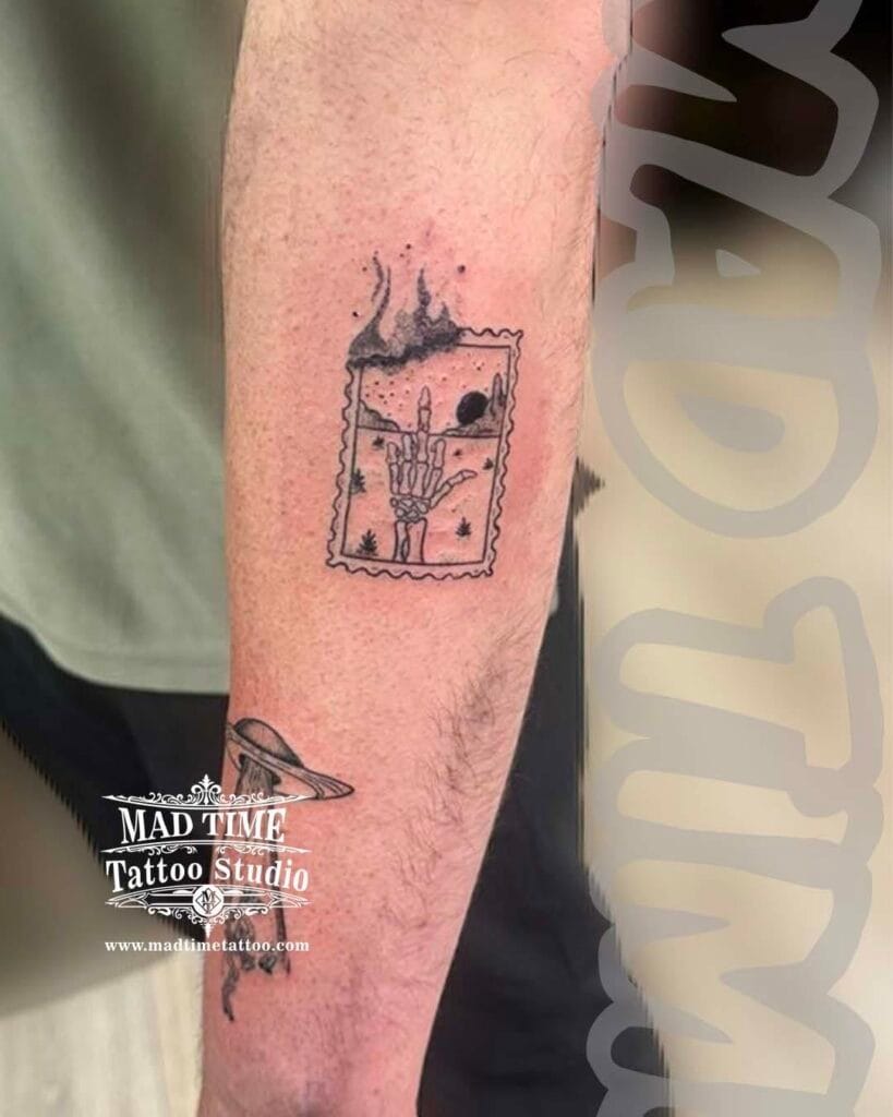 Blackwork graphic tattoo of a burning polaroid photo frames or matchbox with fire details on a forearm.
