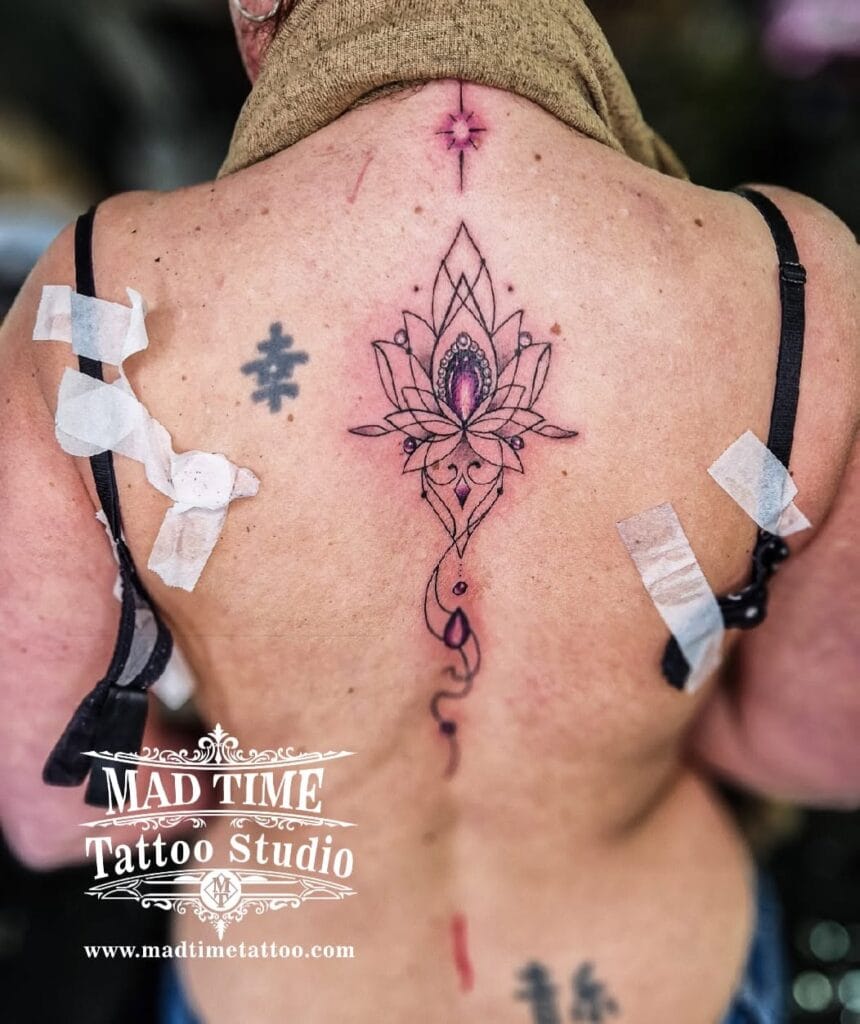 Detailed fine line ornamental mandala tattoo on the upper back between the shoulder blades.