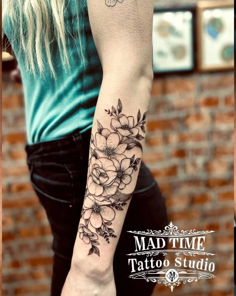 Detailed fine line botanical forearm tattoo with dark leaves and elegant floral compositions.