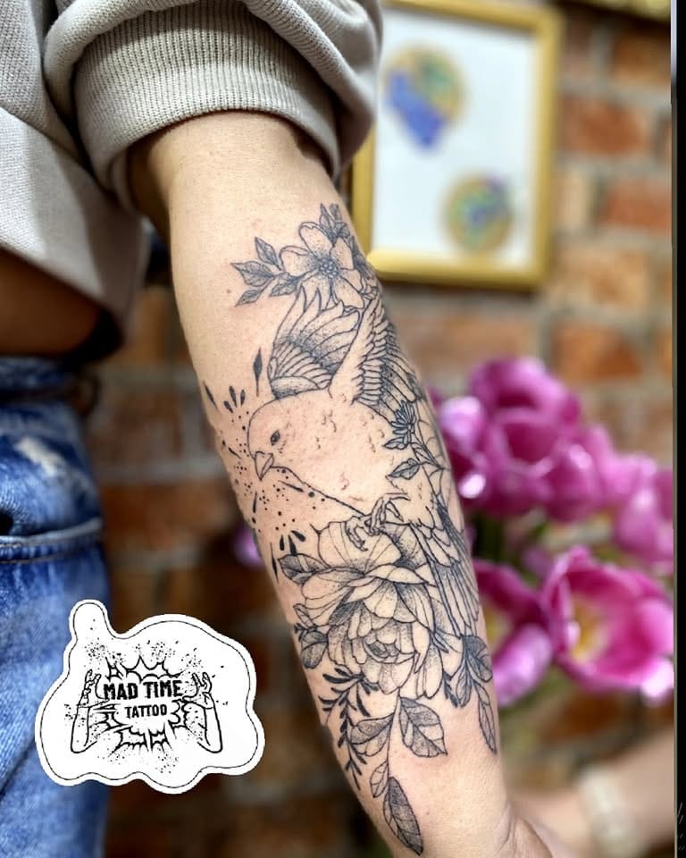 Elaborate fine line floral tattoo covering the lower forearm with blooming flowers and intricate leaf patterns.