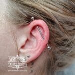 36Professional Piercing Liverpool home new ognialna zagubiona 36 kafelkow Professional industrial ear piercing showcase at Mad Time Tattoo Studio, featuring a straight titanium barbell barbell running through the upper ear cartilage of a female client, with a standard lobe piercing stud below.
