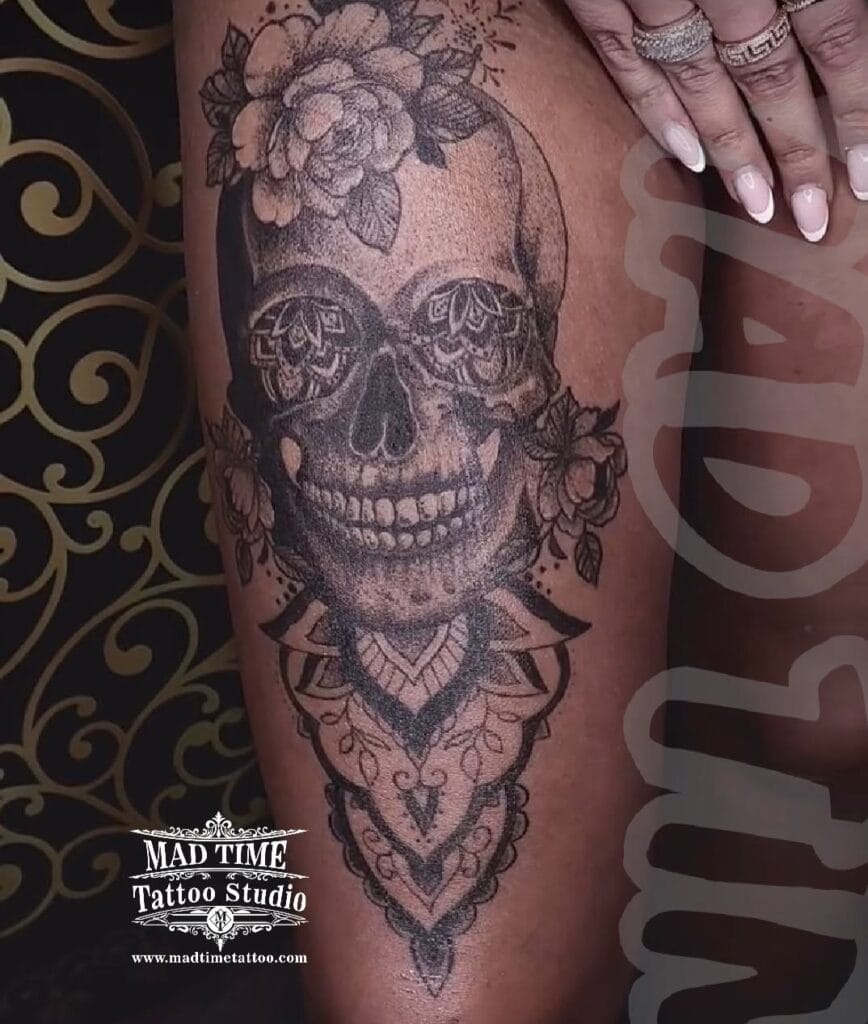 Large ornamental thigh tattoo featuring a highly detailed Santa Muerte sugar skull surrounded by geometric mandala patterns on a leg.