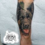 Home new Highly detailed realism pet portrait tattoo of a German Shepherd dog with a happy expression and tongue out, inked on a forearm by Mad Time Tattoo.