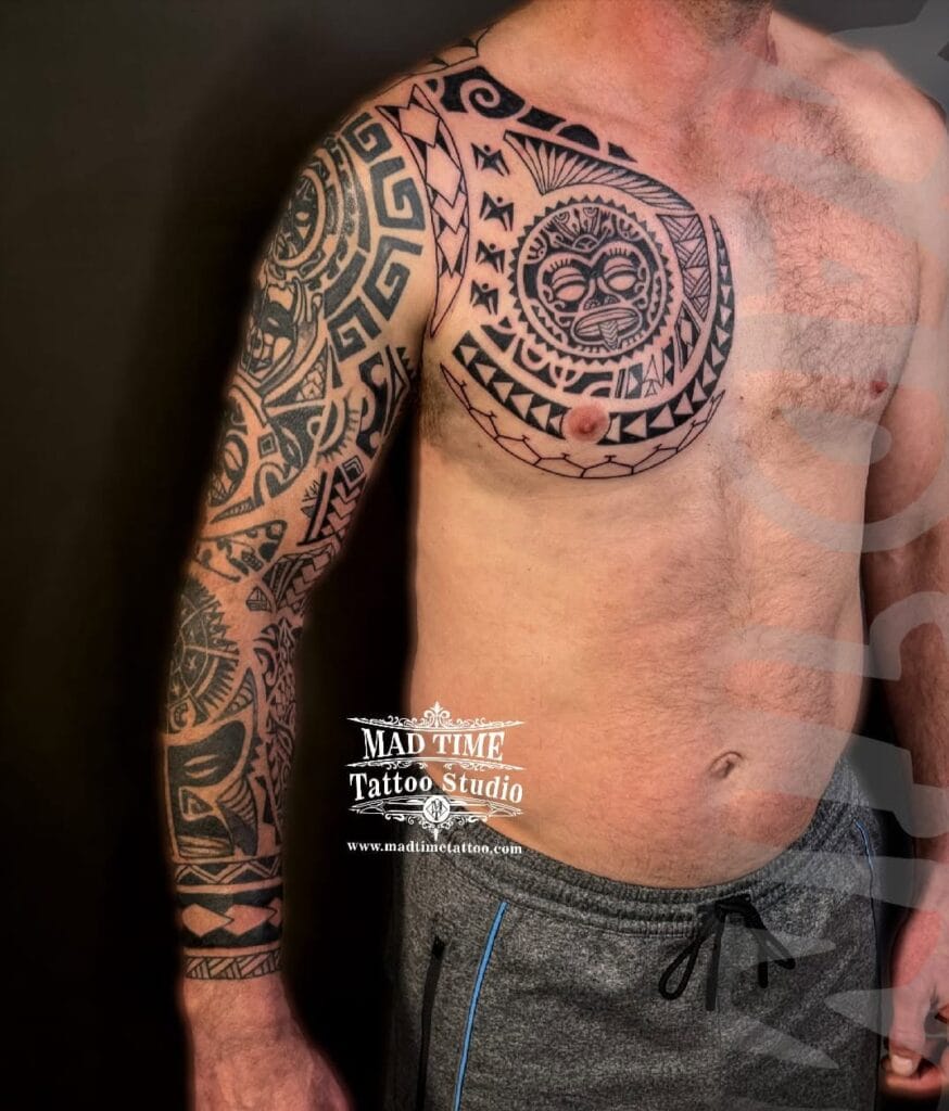 Large Polynesian tribal tattoo extending across a man's chest, shoulder, and down the full arm.