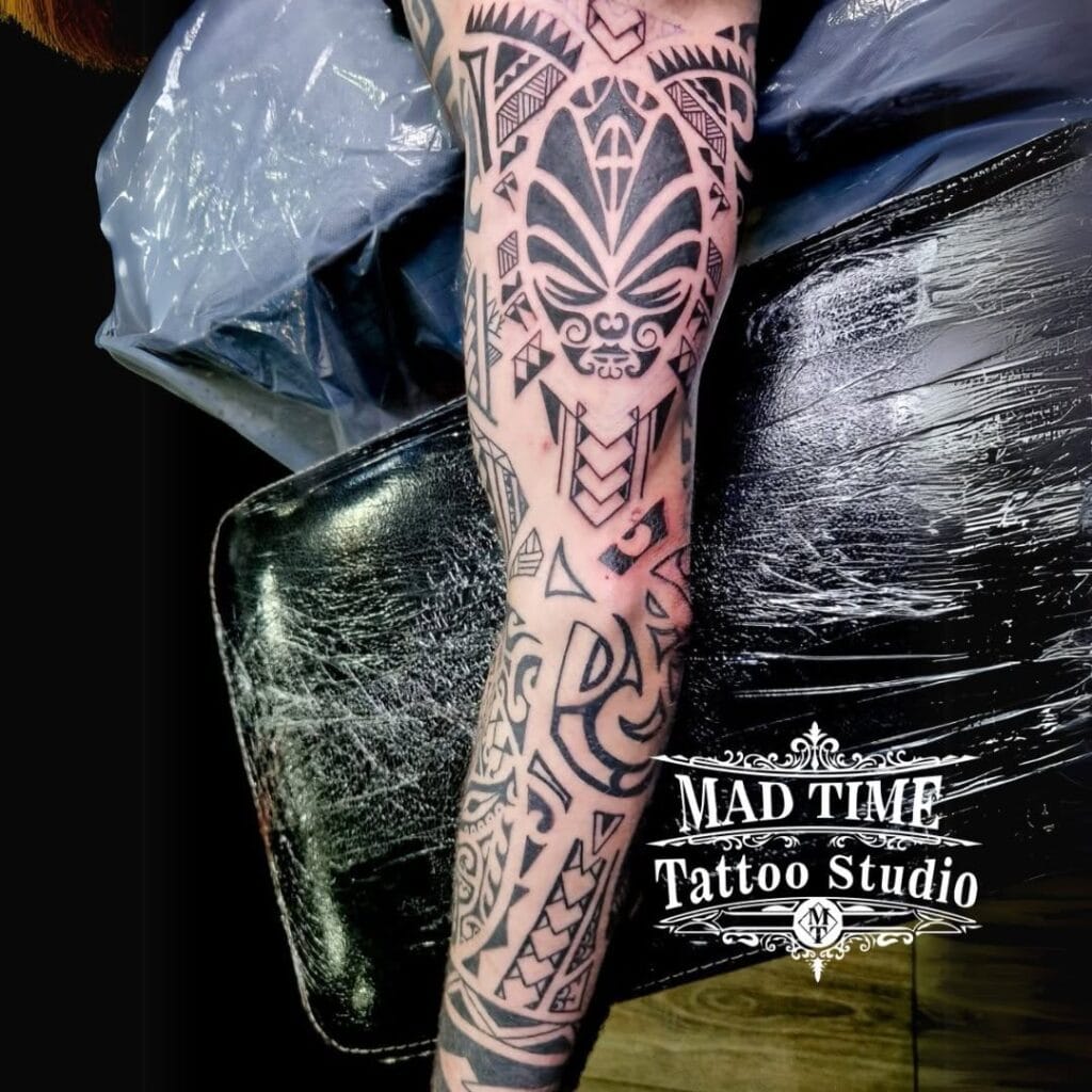 Detailed black ink Polynesian full arm sleeve tattoo with traditional tribal geometric patterns.