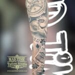 Home new Masterpiece black and grey realism forearm sleeve tattoo by Mad Time Tattoo featuring a vintage compass, detailed portrait of a woman, personalized names with dates, and a realistic human eye near the wrist.