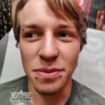 36Professional Piercing Liverpool home new ognialna zagubiona 36 kafelkow Professional facial piercing showcase by Mad Time Tattoo, featuring symmetrical snake bites lip piercing studs, a black nostril hoop ring, and a vertical eyebrow piercing on a male client.