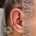 36Professional Piercing Liverpool home new ognialna zagubiona 36 kafelkow • Professional snug piercing showcase by Mad Time Tattoo Studio, featuring a classic titanium hoop ring running horizontally through the antihelix ridge, paired with a luxury gold heart clicker with clear crystals in the rook cartilage on a female client.