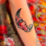 Home new Colorful traditional tattoo of a crescent moon with a woman's face and red roses on a shoulder.