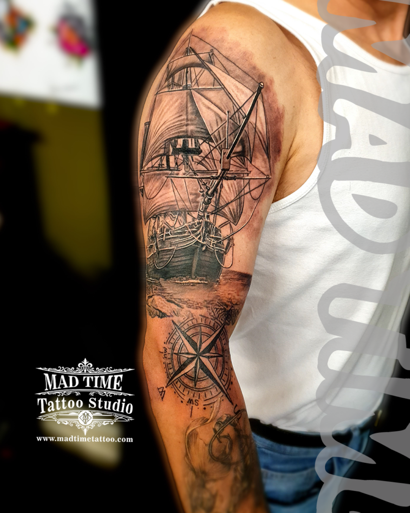 • Detailed black and grey realistic galleon pirate ship tattoo on upper arm paired with a geometric vintage compass windrose by resident artist Henry at our studio