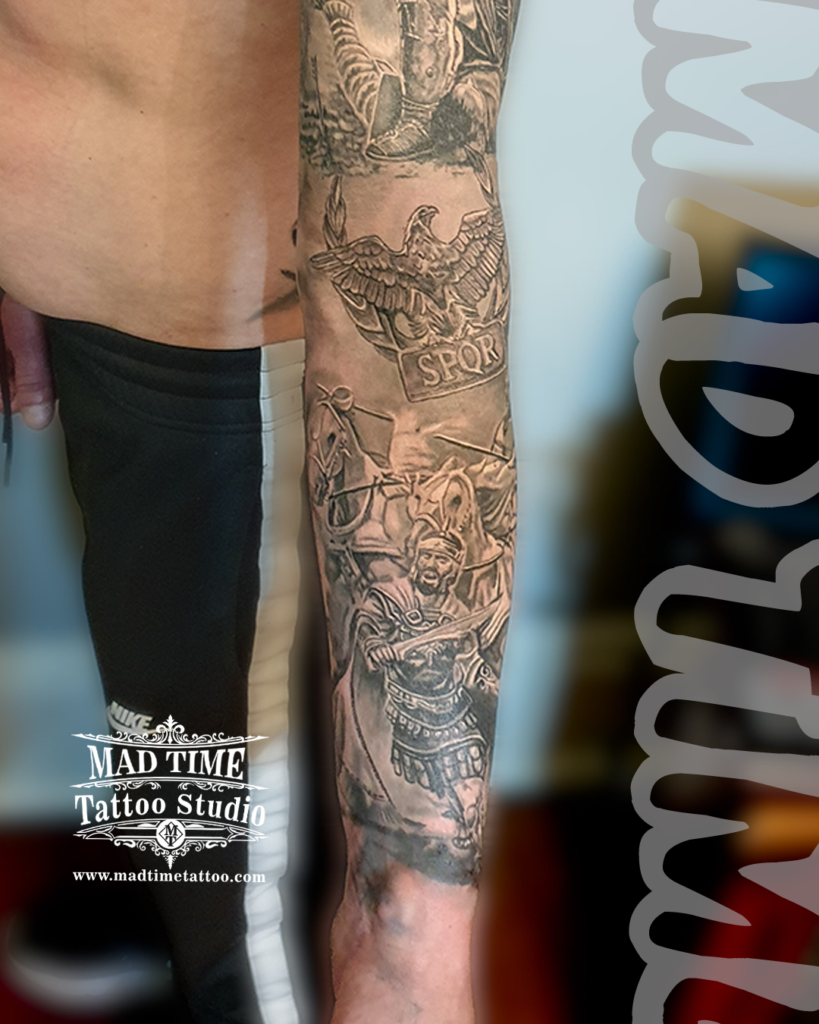 • Detailed black and grey realism forearm tattoo of a Roman centurion soldier holding a sword with charging war horses below an SPQR eagle emblem by resident artist Henry at our studio