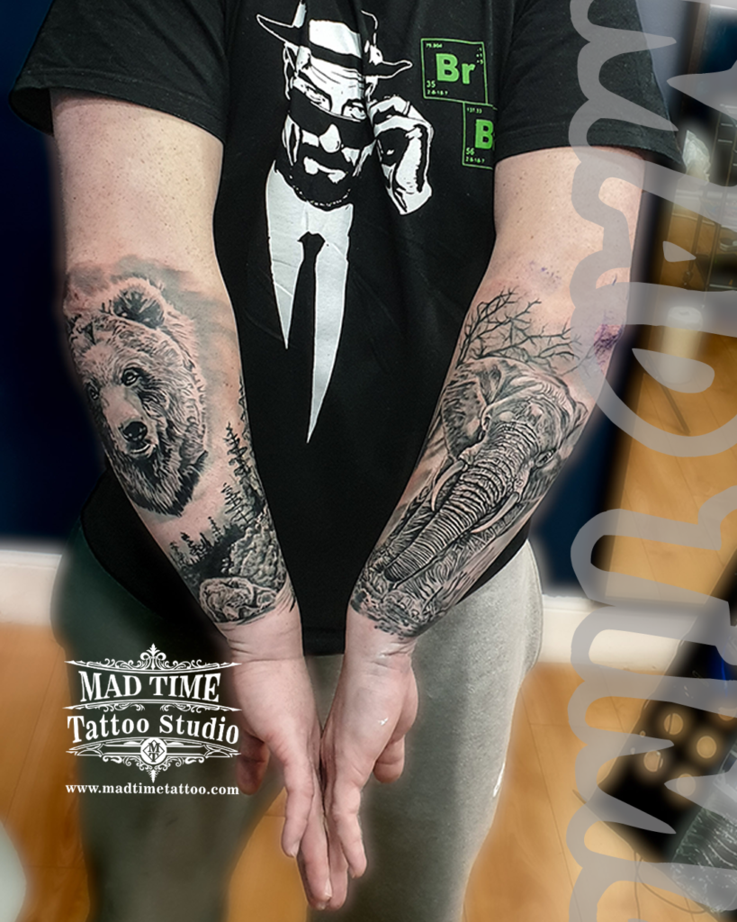 Symmetrical black and grey realism forearm tattoos showcasing a detailed grizzly bear head in a pine forest and a majestic African elephant by resident artist Henry at Mad Time Tattoo Studio