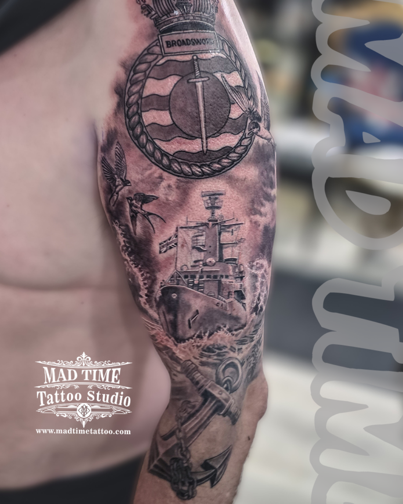 Premium military realism tattoo featuring an HMS Broadsword naval warship navigating rough seas beneath a royal military emblem and a heavy steel anchor by Henry at our studio