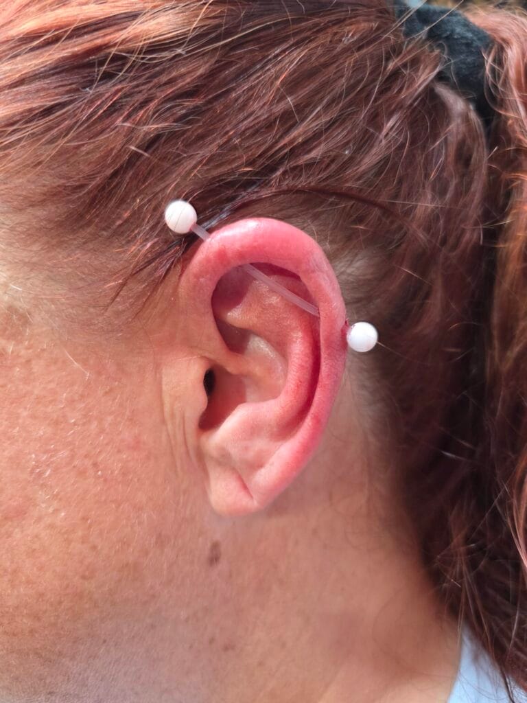 Clear industrial piercing barbell with solid white acrylic balls on the ends
