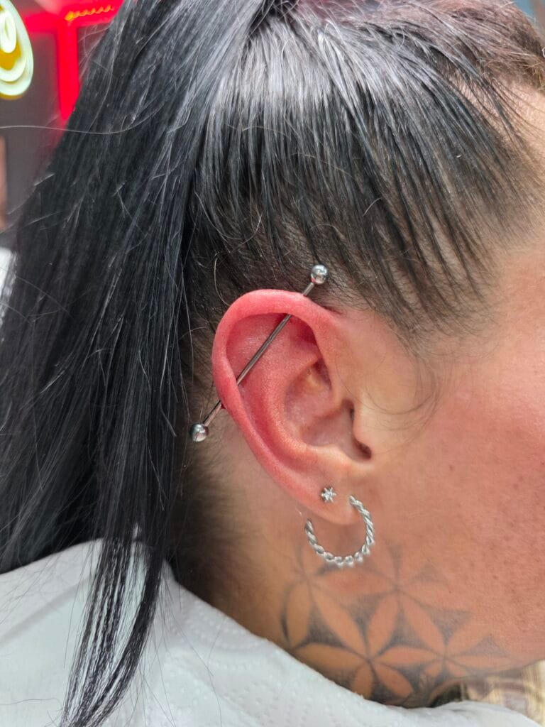 Classic industrial piercing with a straight silver surgical steel barbell in an ear cartilage