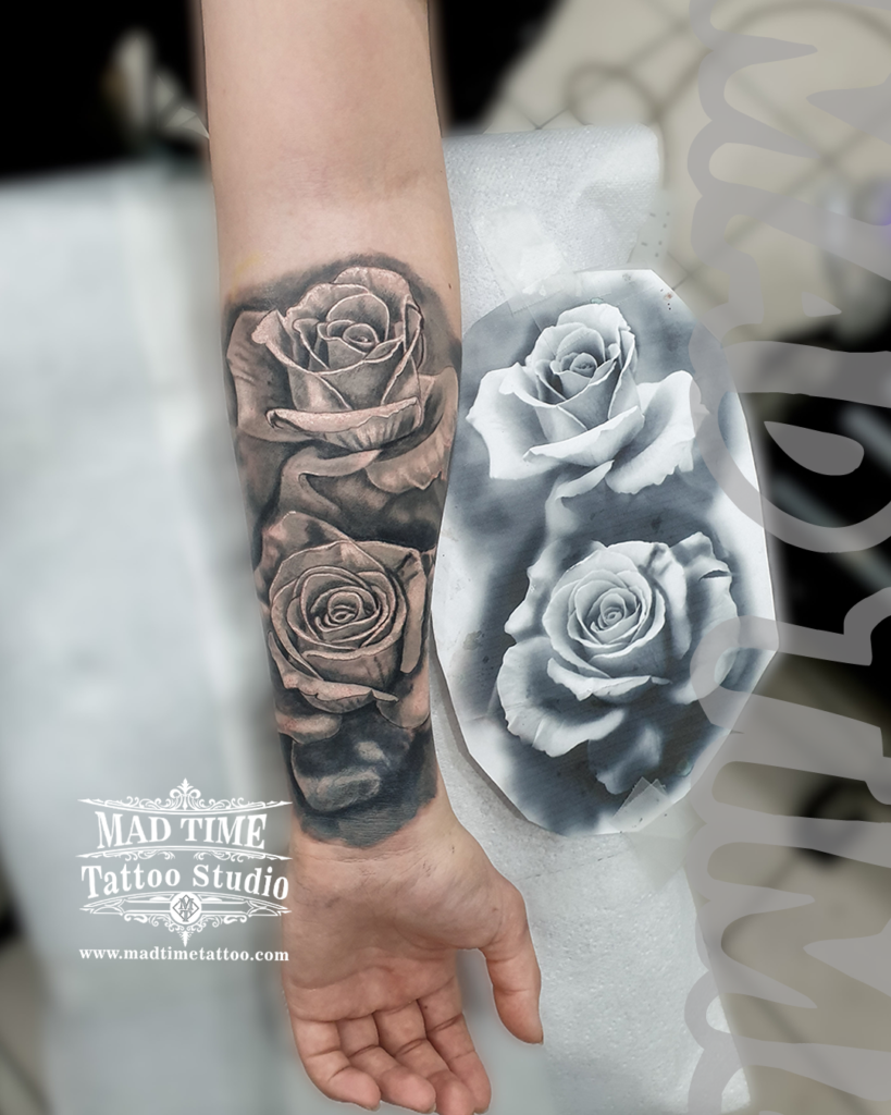 Black and grey realism tattoo of two detailed roses on a forearm shown next to the original paper stencil art mockup by Henry at our studio
