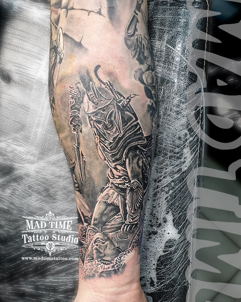 Black and grey realism forearm tattoo of an ancient Greek warrior in armor standing over a fallen statue head face by Henry at our studio
