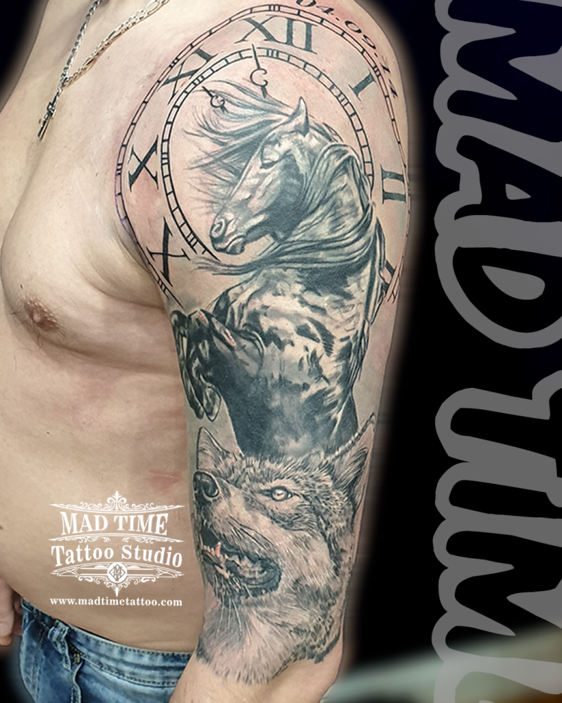 Detailed black and grey realism upper arm tattoo showcasing a powerful rearing stallion horse with a flowing mane inside a Roman numeral clock and a wolf profile by Henry at Mad Time Tattoo Studio