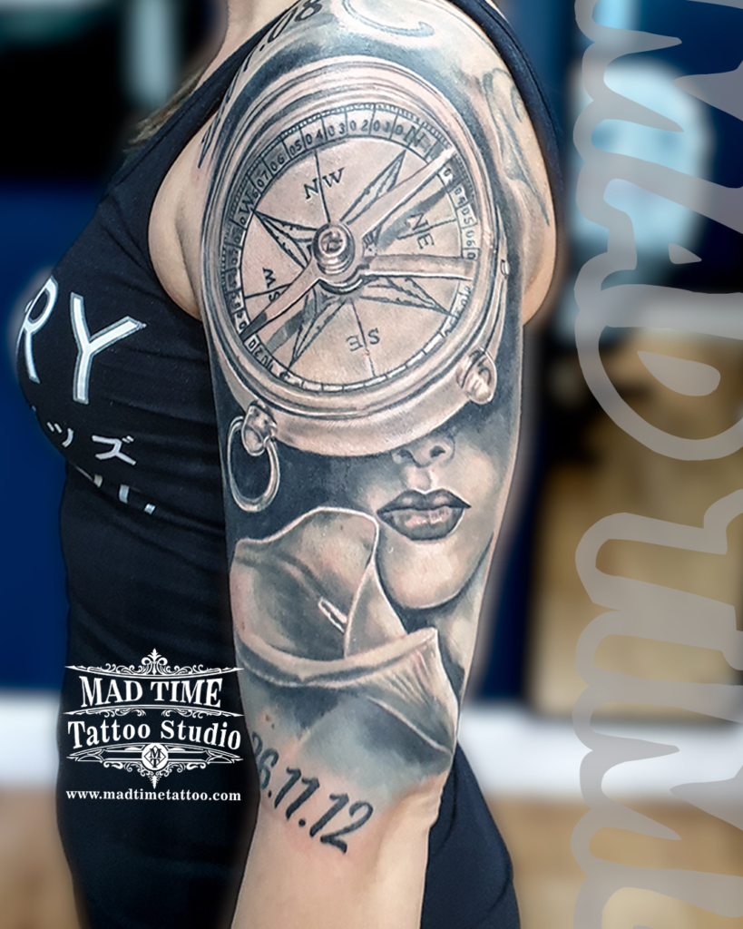 Black and grey surreal realism sleeve showcasing a woman's eyes beneath a detailed maritime compass and a soft rose by Henry at our studio