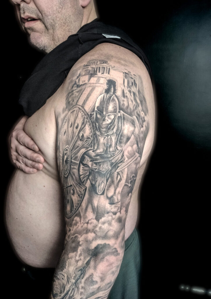 Detailed black and grey Spartan warrior tattoo with shield and ancient temple background by guest artist Pablo from Spain at our studio