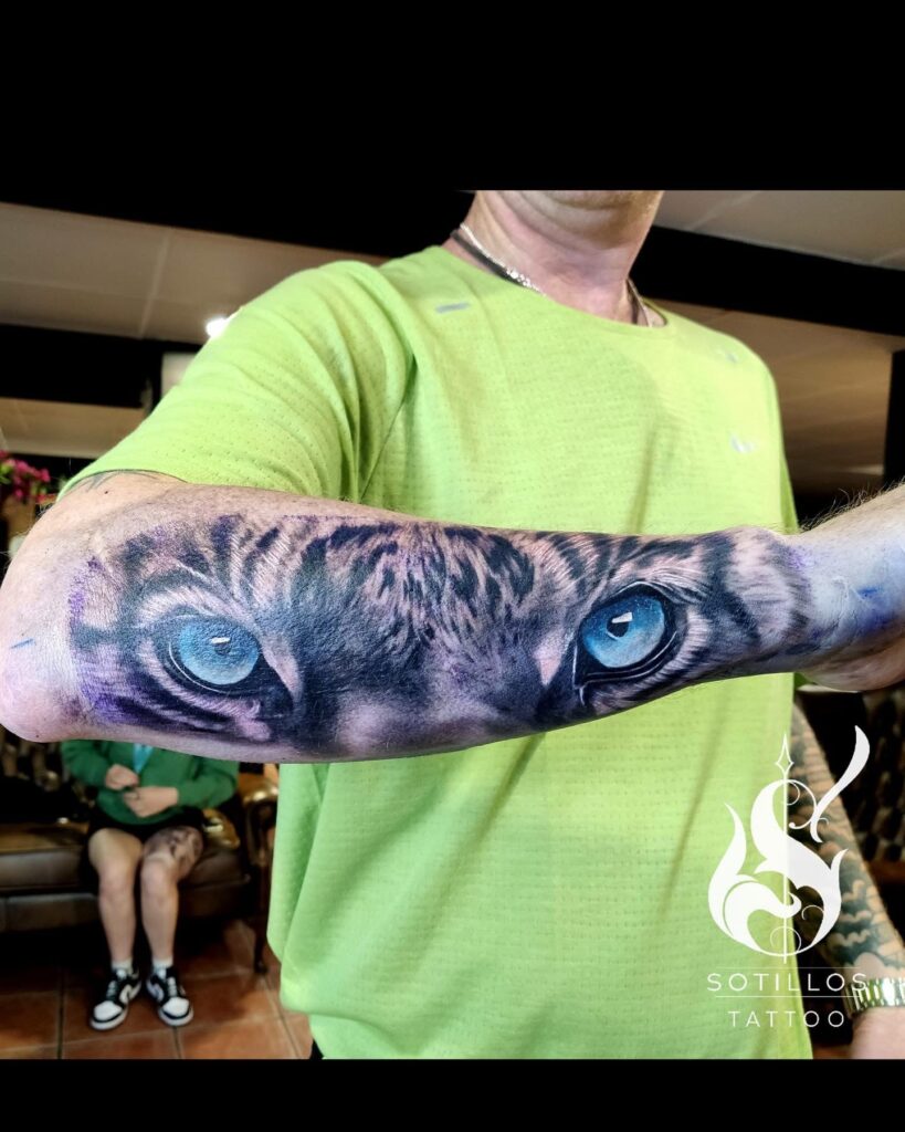 Tiger eyes realism forearm tattoo featuring striking blue eyes accents by guest artist Pablo from Spain at our studio