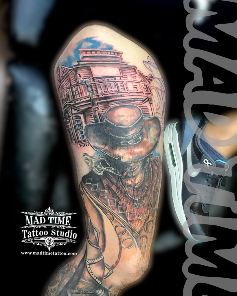 • Pop culture gaming tattoo of a cowboy outlaw wearing a Stetson hat smoking a cigar in front of a Western saloon building by our studio