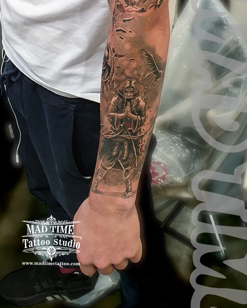 Anime Tattoos Liverpool • Detailed black and grey realism forearm tattoo of Itachi Uchiha making hand signs surrounded by crows and falling leaves by resident artist Henry at Mad Time Tattoo Studio