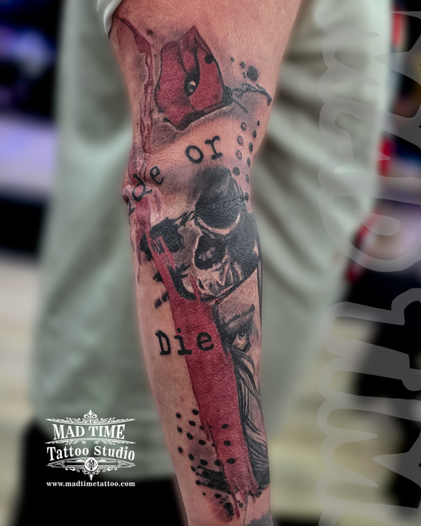 • Trash Polka style tattoo on an arm featuring a realistic black and grey skull beneath typewriter text reading Ride or Die layered with chaotic blood red brush strokes and paint dots by our studio