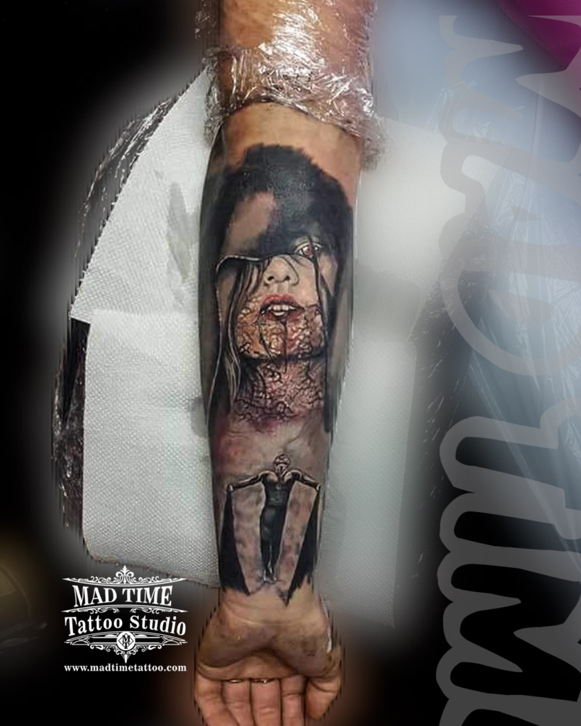 Silent Hill movie horror realism forearm tattoo of the burnt demonic face of Alessa Gillespie above a dark crucified figure silhouette by our studio